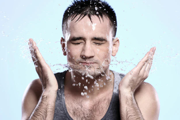 A guy splashing water on face | effects of hard water on skin