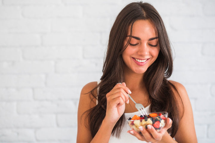 a girl eating a bowl of healthy food to keep her hair healthy
