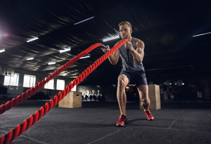 a man doing battle ropes in gym