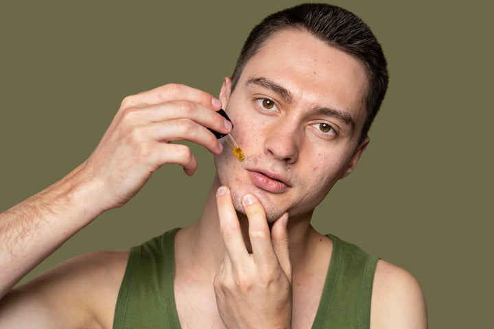 a man applying vitamin c serum on his face to get even skin