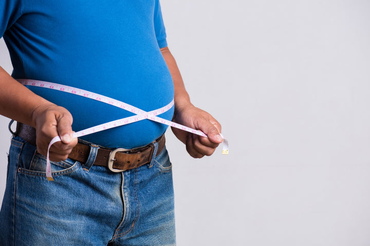 a man measuring his fat belly using a measuring tape
