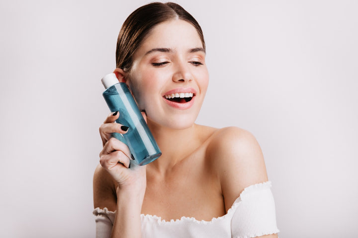 a woman holding a toner bottle near her face