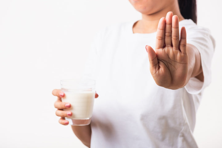 a woman holding a glass of milk in one hand and her other hand is showing a sign of stop