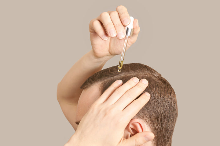 a man applying oil on his hair using a dropper